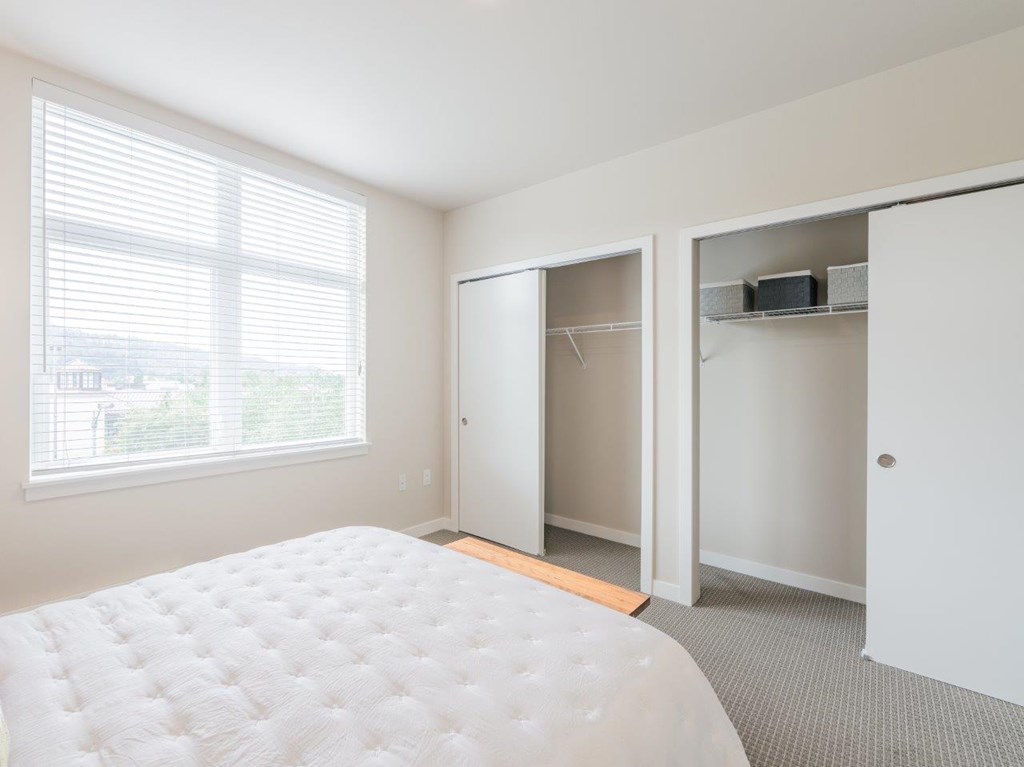 A white bed with a white mattress in a room with a window.