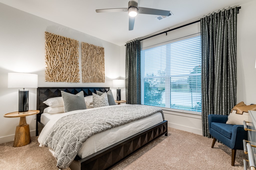 Aura 3Twenty Apartments bedroom with a large window and a bed and a ceiling fan