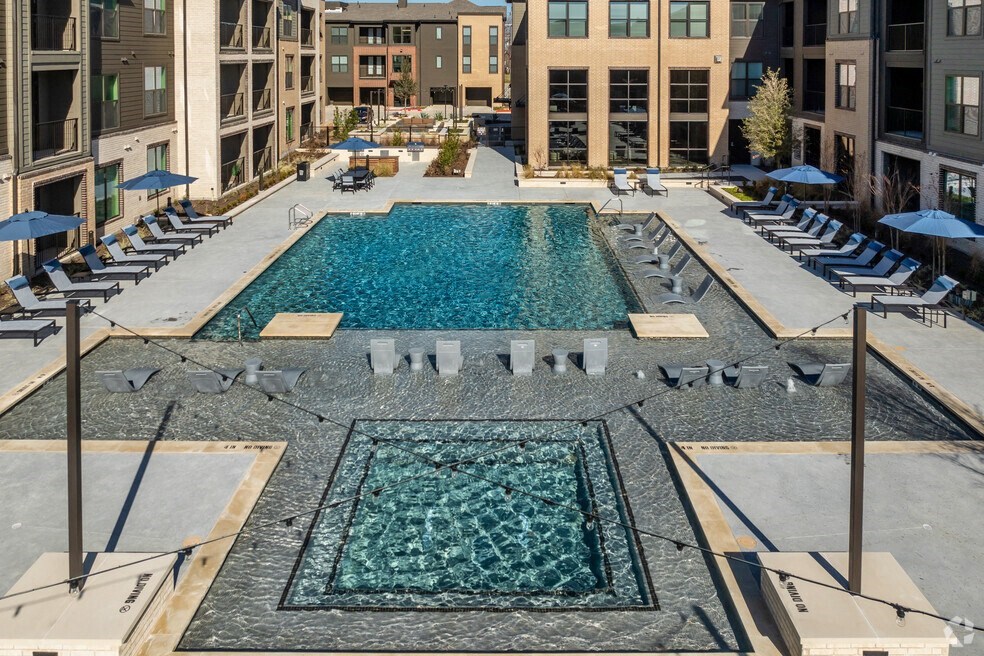 a swimming pool with lounge chairs and umbrellas in an apartment building