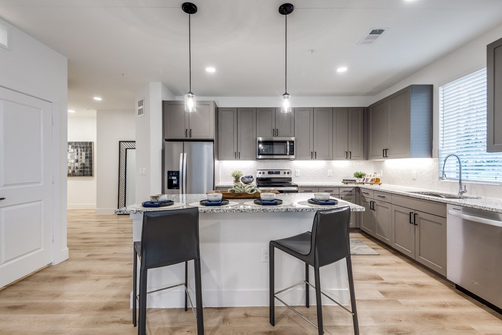 Aura 3Twenty Apartments  open kitchen with a large island with two stools