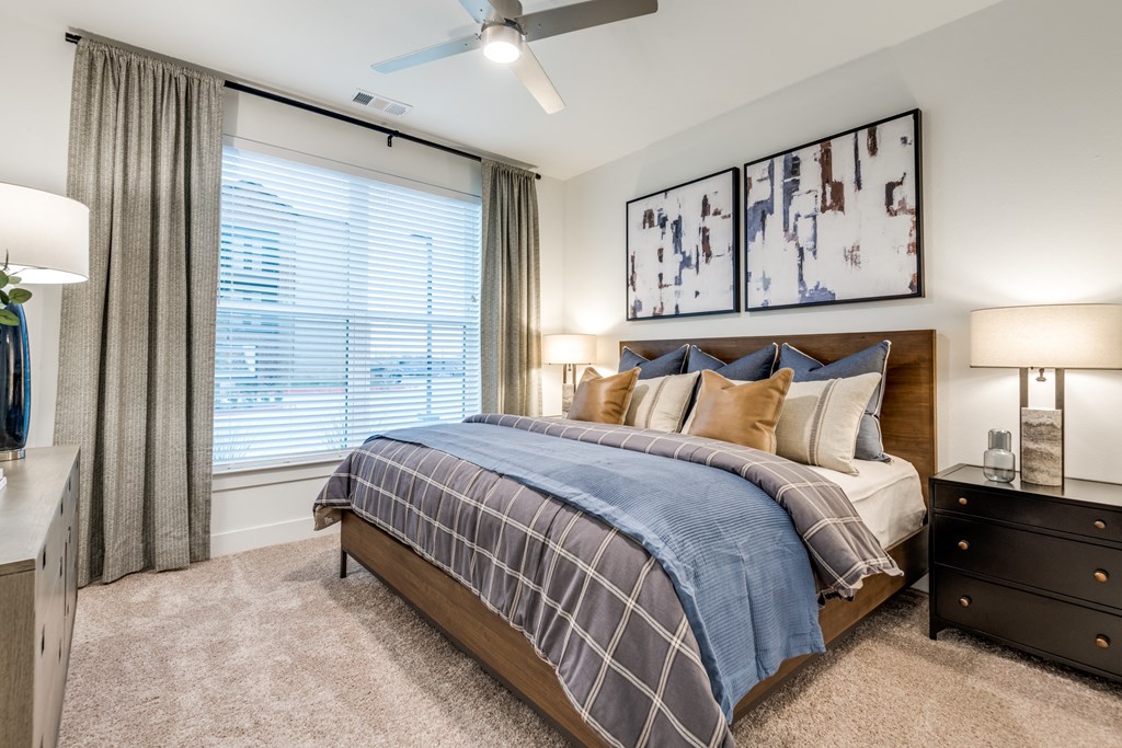 Aura 3Twenty Apartments bedroom of a model home with a bed and a large window