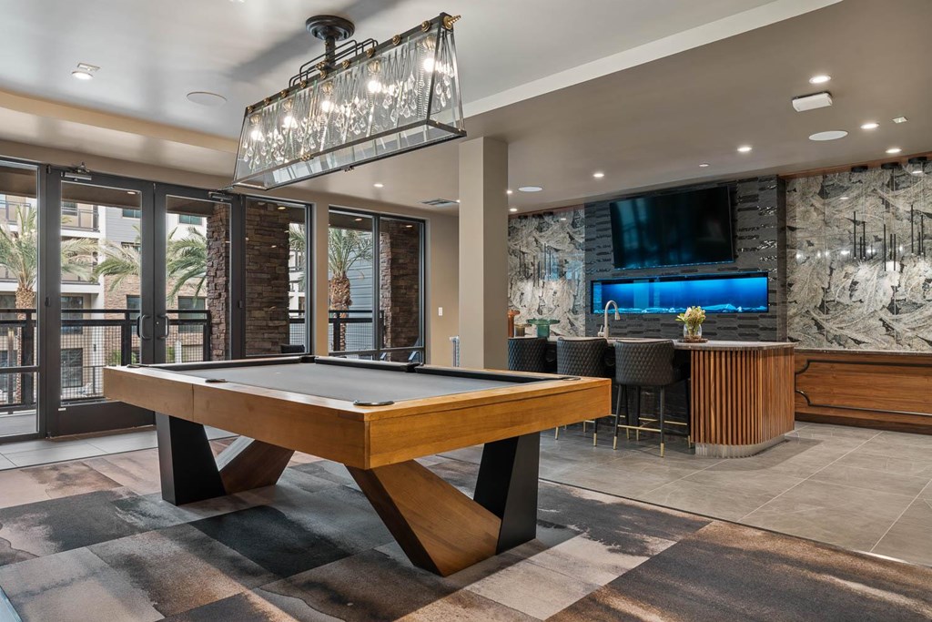 A pool table in a room with a TV and a bar.