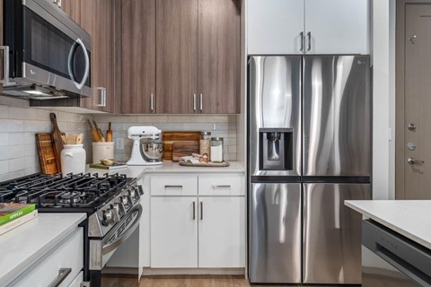 A modern kitchen with a stainless steel refrigerator and white appliances.