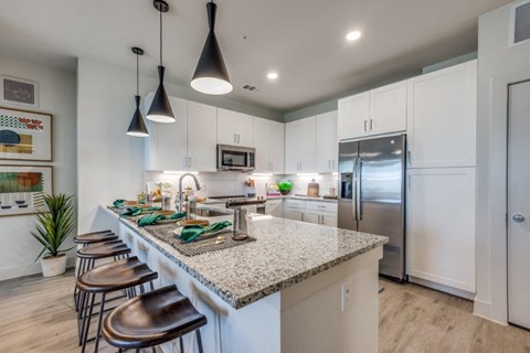 a kitchen with a marble counter top and a stainless steel refrigerator