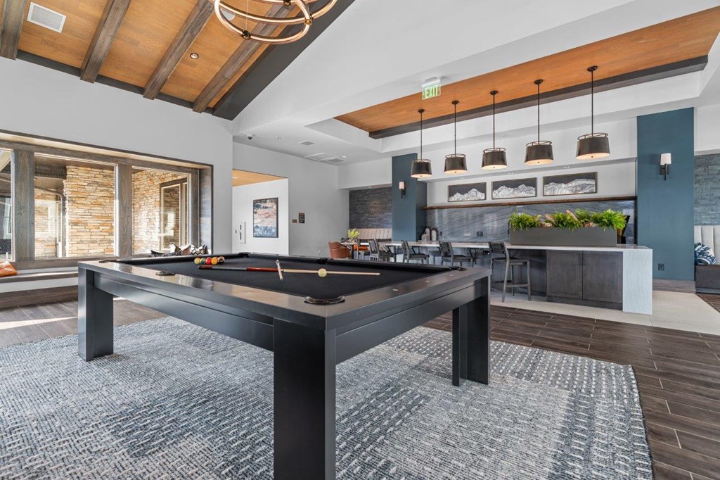a pool table in a living room with a bar