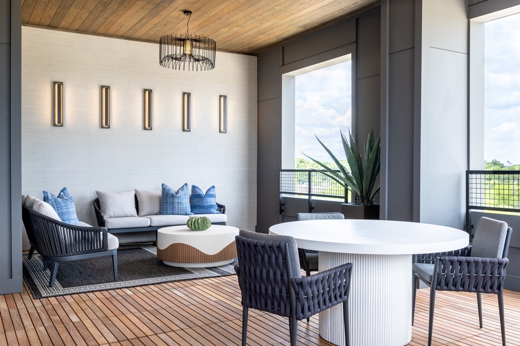 A modern living room with a white sofa, a round table, and a wooden ceiling.