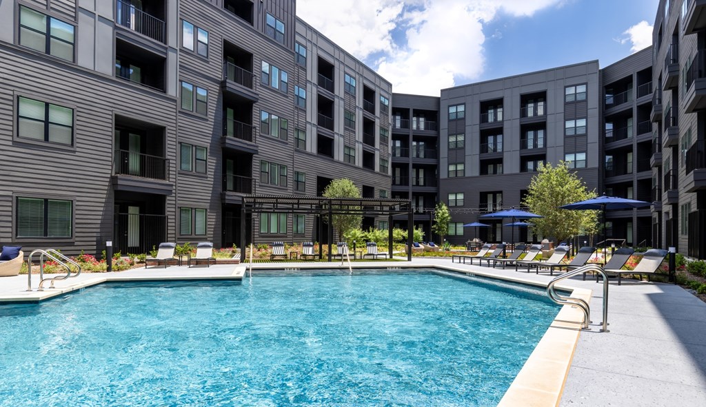 A large swimming pool is surrounded by apartment buildings.