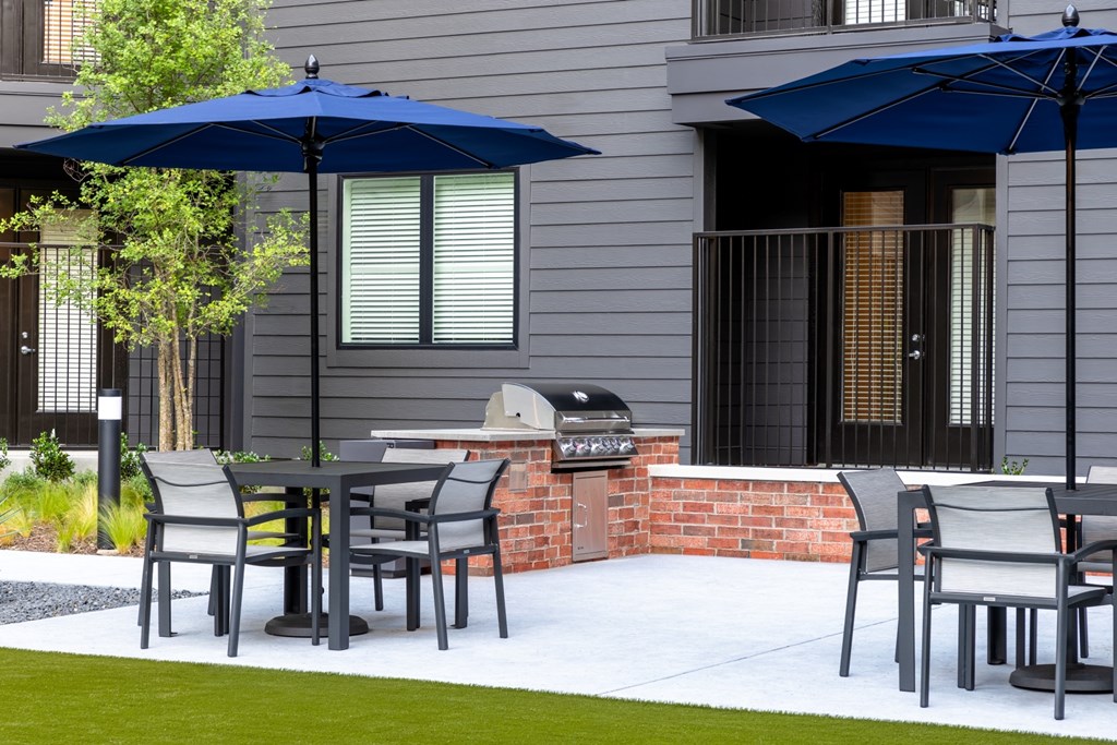 A patio with a table and chairs under blue umbrellas.