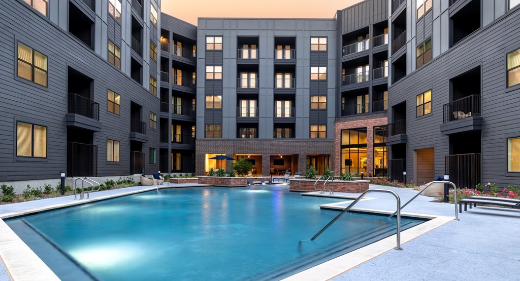 A large swimming pool is surrounded by apartment buildings.