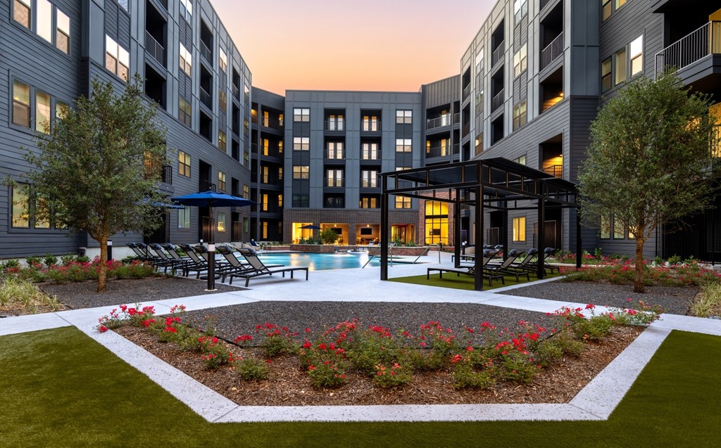 A modern building with a pool and a garden in front.