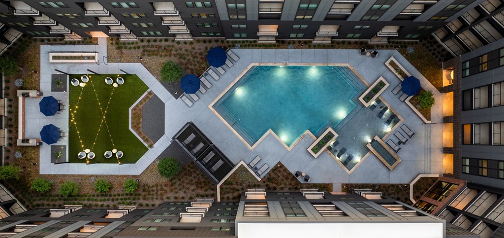 A large swimming pool surrounded by a patio area with chairs and a table.