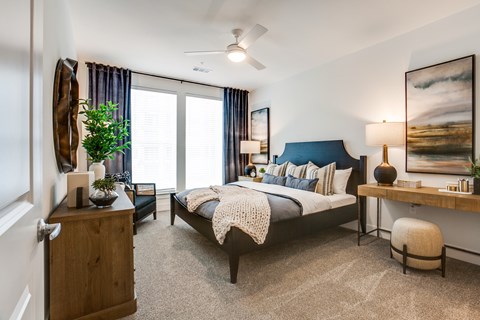 A bedroom with a bed, nightstand, and a painting on the wall.