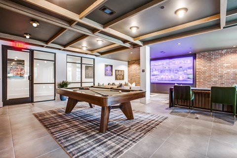 A room with a pool table and a bar area.