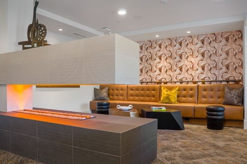 A modern living room with a brown sofa and a wooden sculpture on the wall.