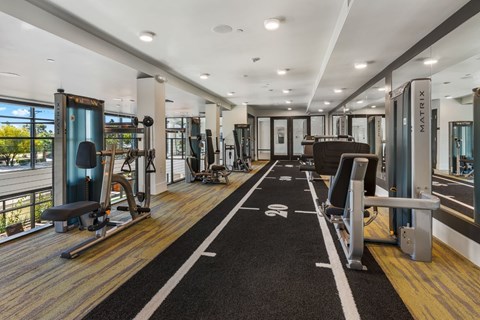 A gym with a variety of equipment including treadmills, weights, and exercise machines.