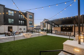 A patio area with a lawn and string lights.
