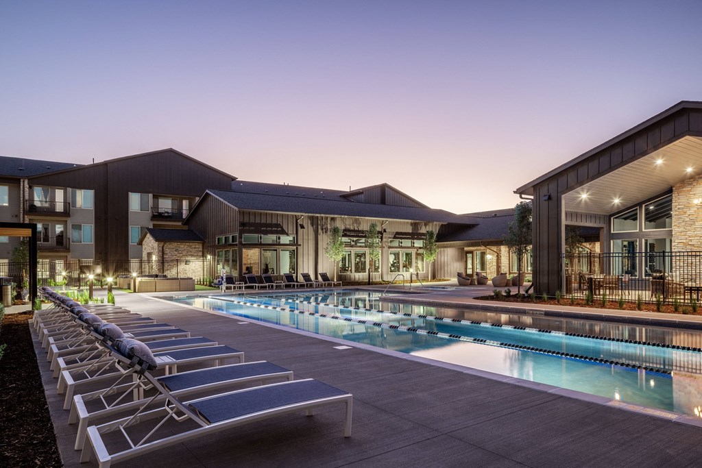 a swimming pool with lounge chairs in front of a building
