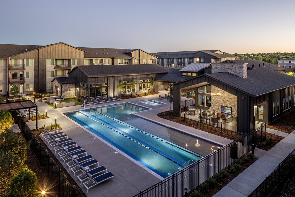 an aerial view of a swimming pool at night with apartments in the background