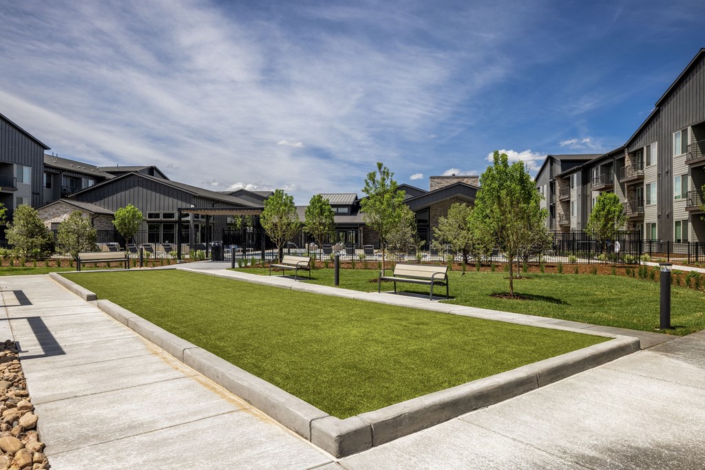 a park with green grass and benches in front of buildings