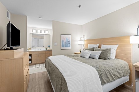 A bedroom with a large bed and a television on a cabinet.