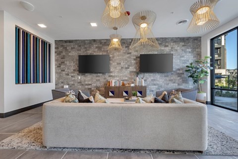 A modern living room with a grey sofa and a stone wall.