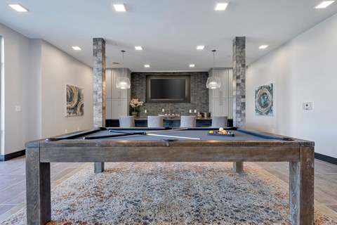 A pool table in a room with a stone pillar and a television mounted on the wall.
