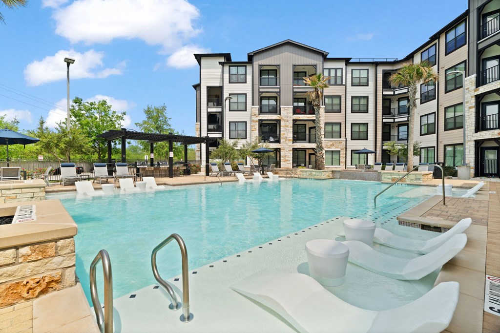 A large swimming pool with a slide in front of a multi-story apartment building.