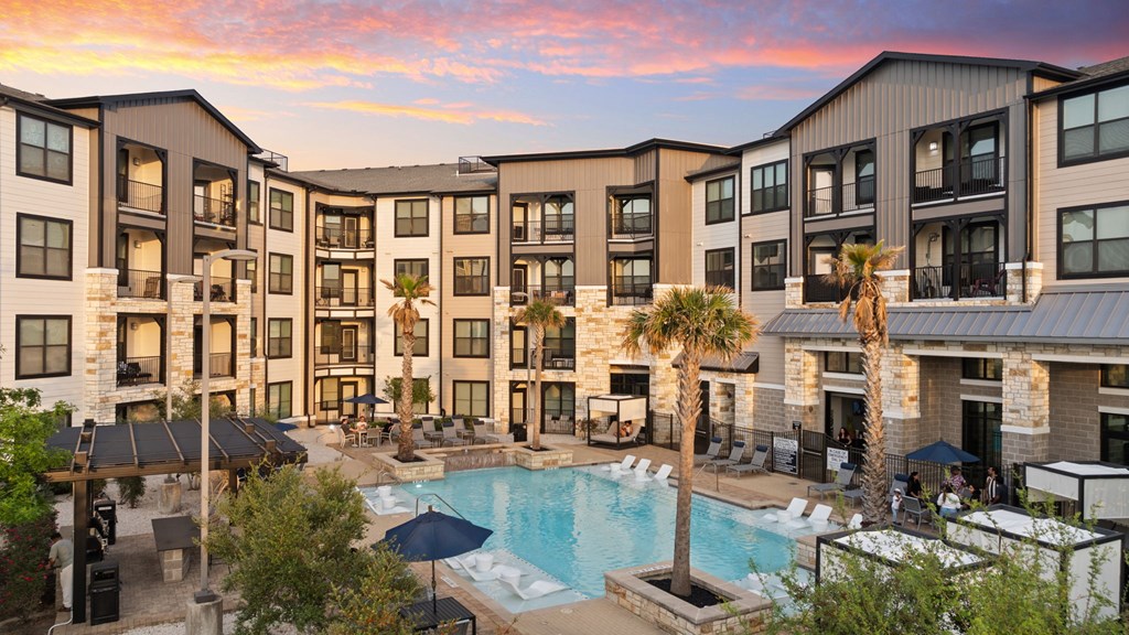 A large apartment complex with a pool in the foreground.