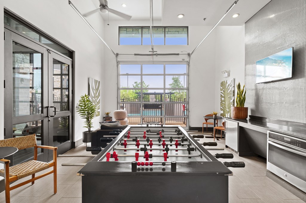 A foosball table is in the middle of a room with a chair and a plant.