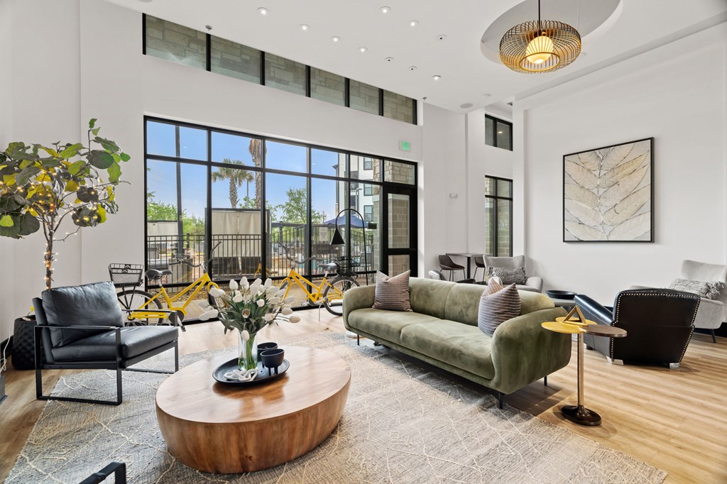 A living room with a green couch, a coffee table, and a large window.