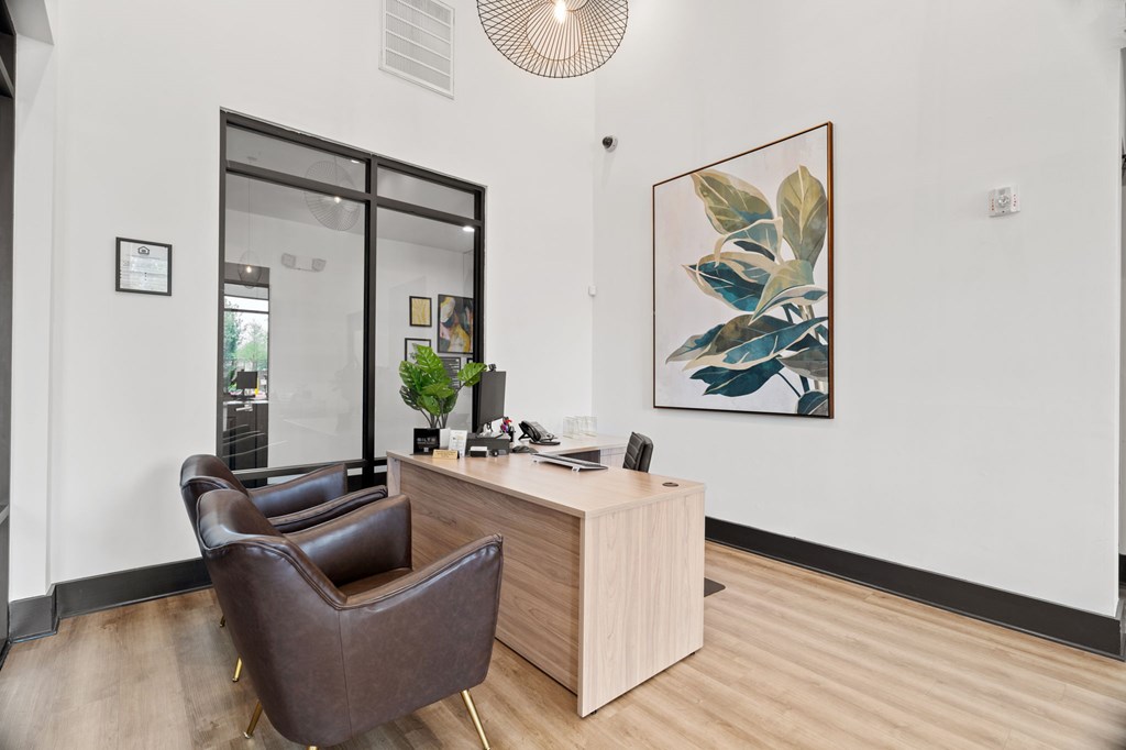 A brown leather chair sits in front of a wooden desk with a plant on it.