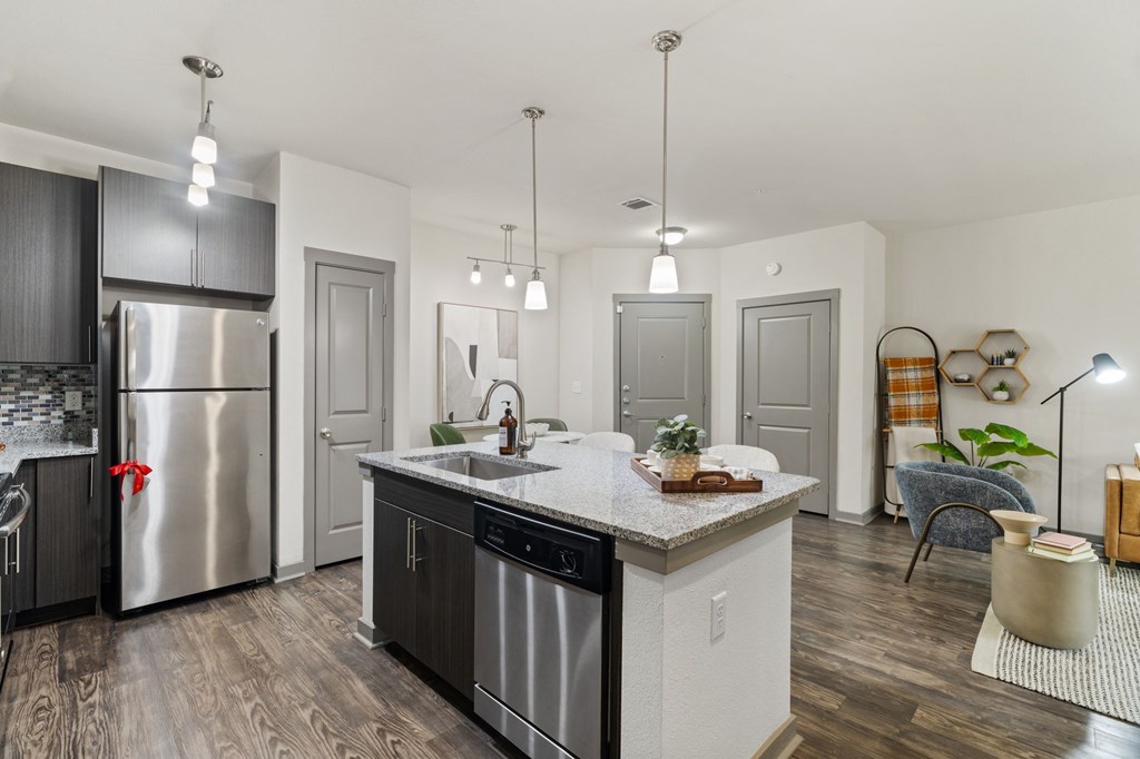 A modern kitchen with a stainless steel refrigerator and wooden flooring.