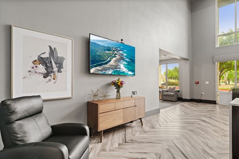 A living room with a black leather chair, a wooden dresser, and a painting on the wall.
