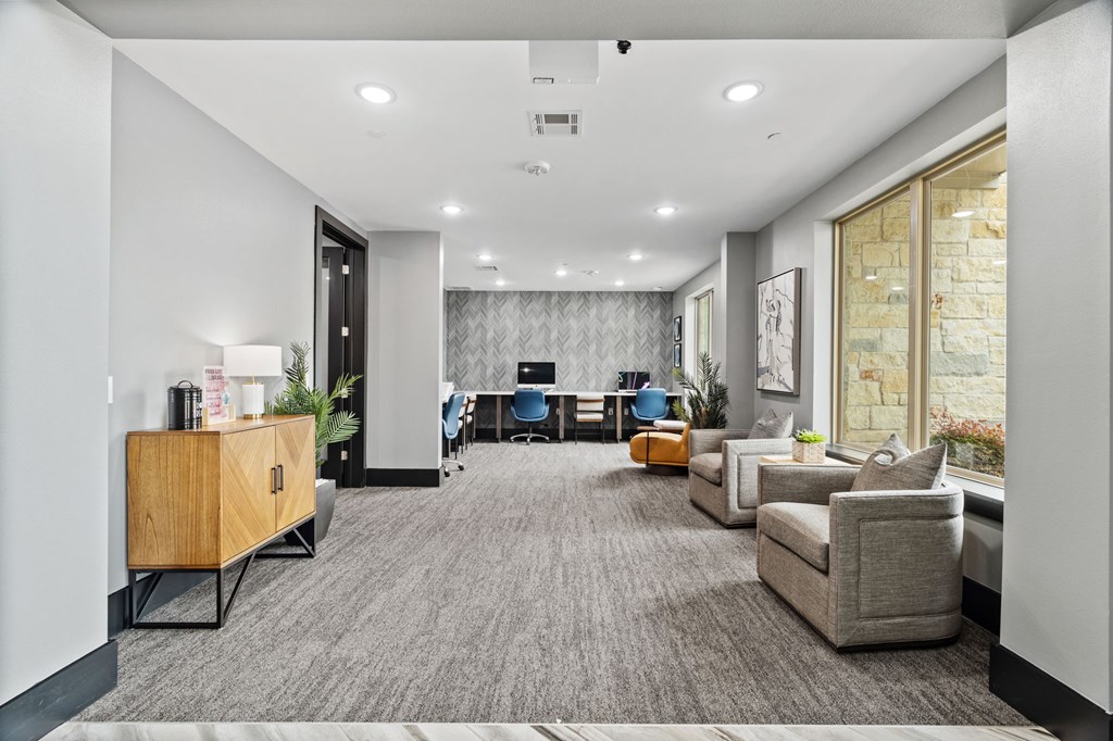 A modern office space with a grey carpet and a variety of seating options.