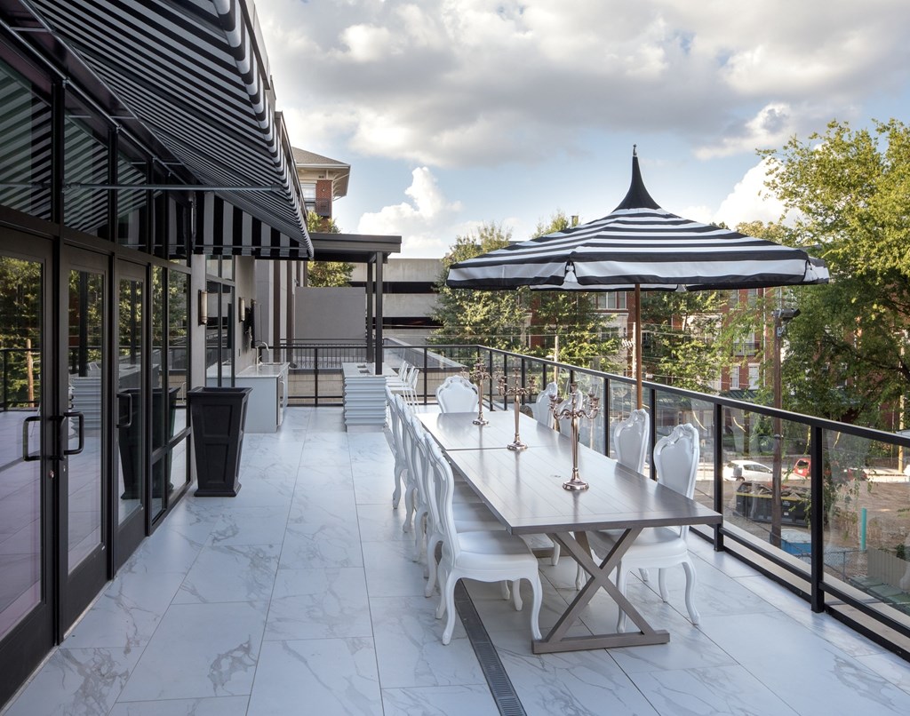 A patio with a table and chairs under a striped umbrella.