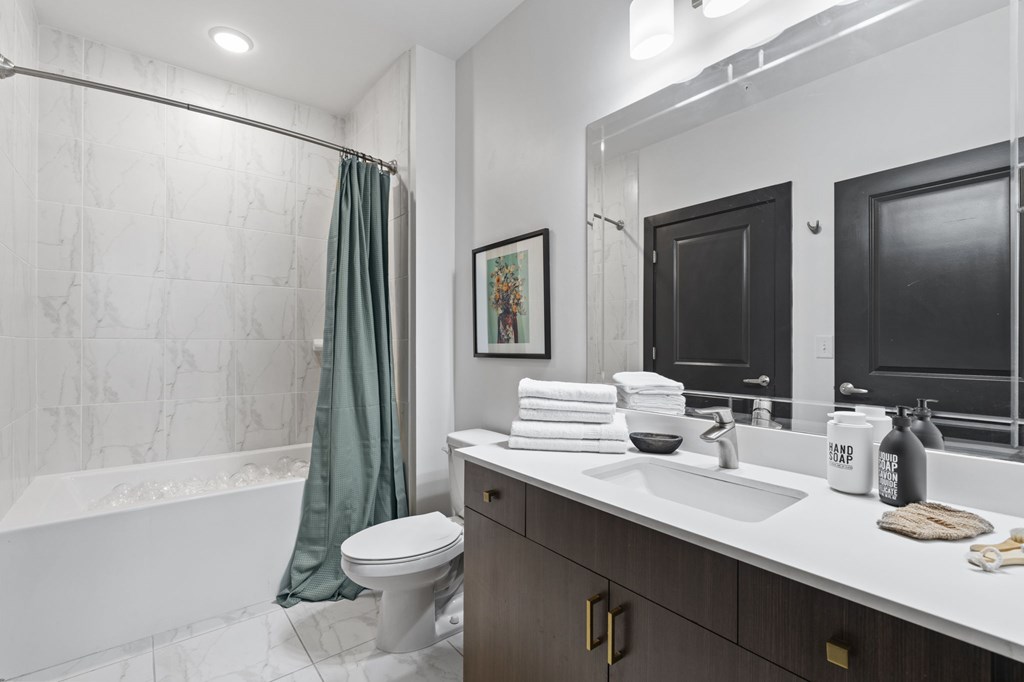 A bathroom with a white tub, sink, and toilet.