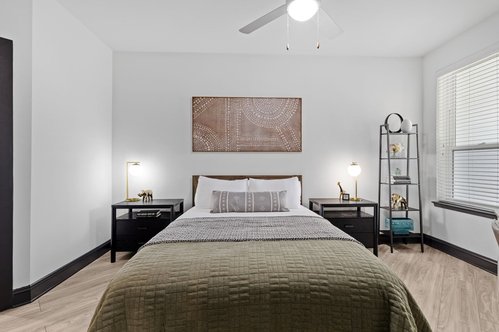 A bedroom with a bed, two nightstands, and a ceiling fan.