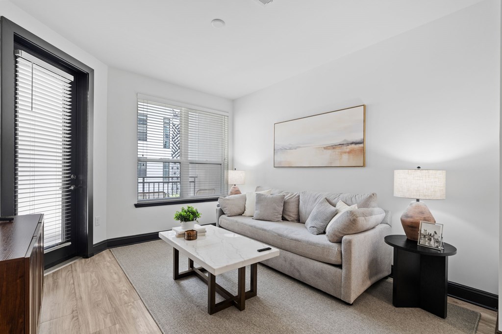 A living room with a couch, coffee table, and a painting on the wall.