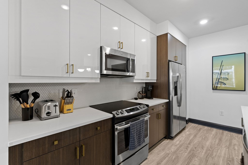 A modern kitchen with white cabinets and a wooden floor.