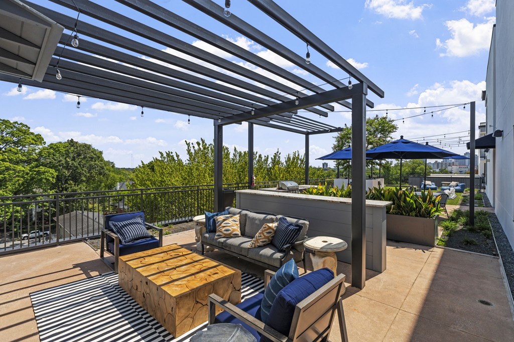 A patio with a wooden table and chairs under a metal roof.