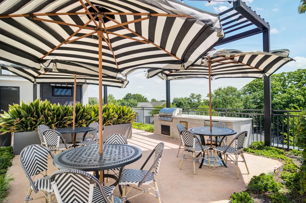 A patio with a table and chairs under striped umbrellas.