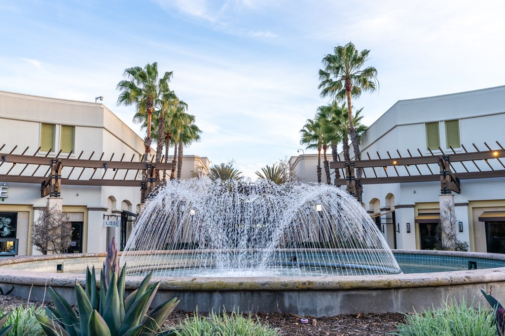 A fountain in the middle of a pool surrounded by palm trees.
