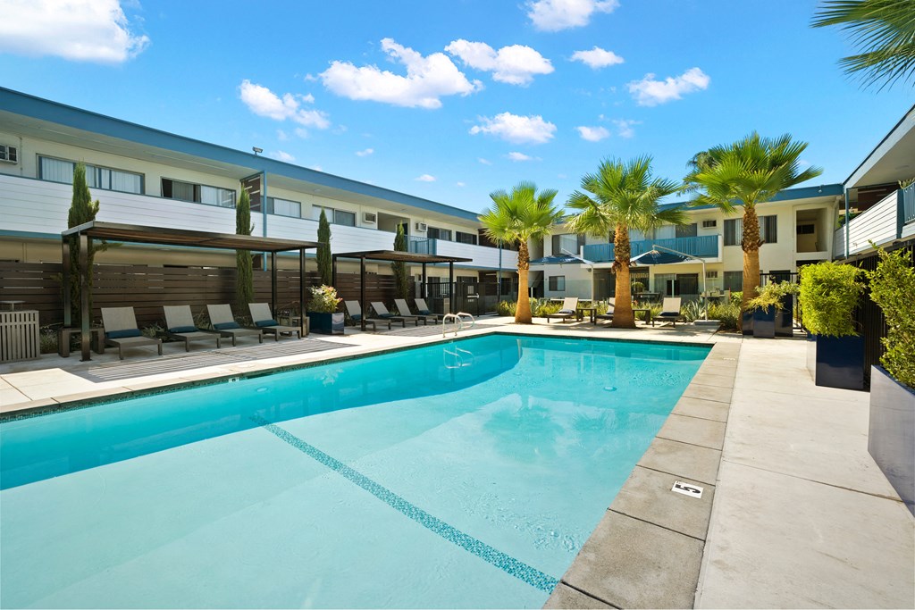 a swimming pool with palm trees and a building in the background