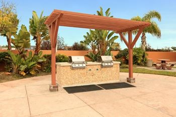 A wooden pergola with a stone pillar and bench underneath it.