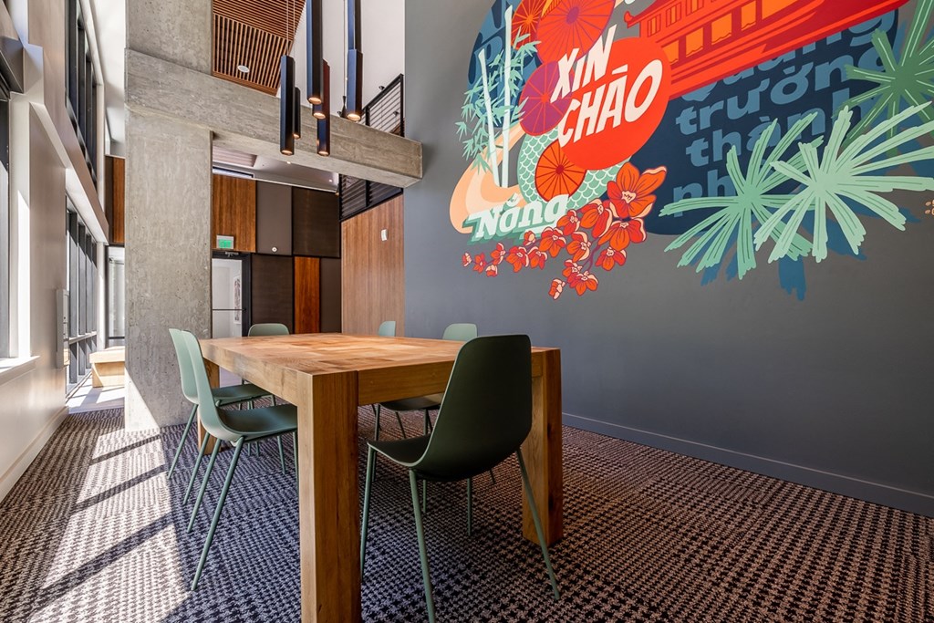 a dining area with a table and chairs and a mural on the wall