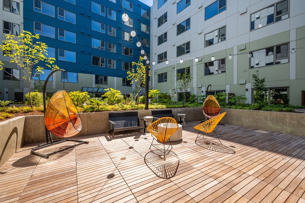 a patio area with chairs and a table in front of an apartment building