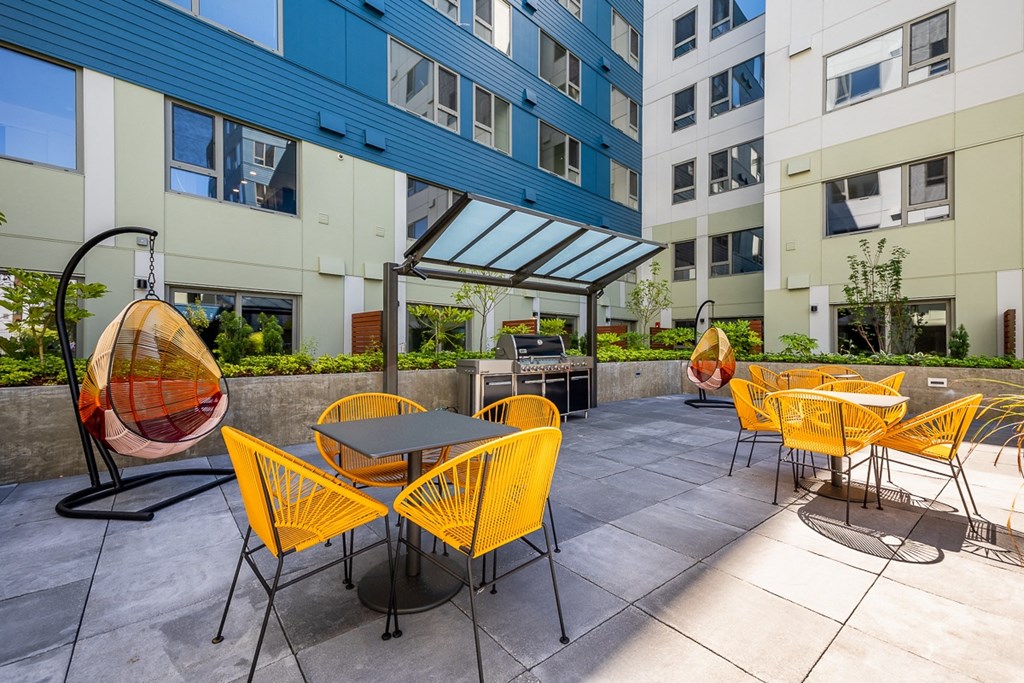 an outdoor patio with yellow chairs and tables at an apartment building