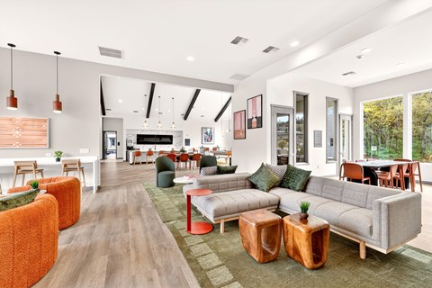A modern living room with a grey sofa and orange ottoman.