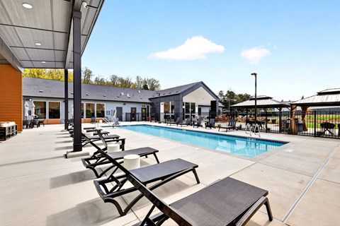 A pool area with sun loungers and a building in the background.