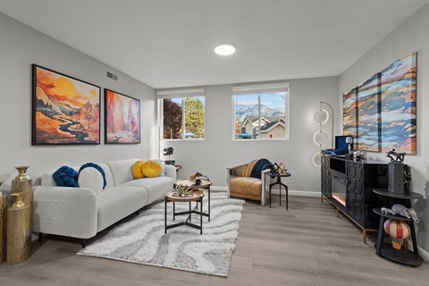 A living room with a white couch, a coffee table, and two paintings on the wall.